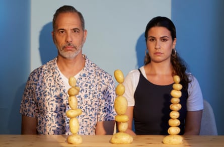 Chefs Yotam Ottolenghi and Noor Murad sitting with three towers of potatoes in front of them