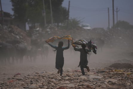 Girls hold scarves above their heads as they walk along a dry path
