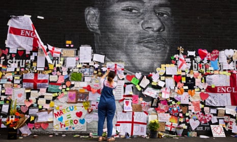 People look at the messages of support and the newly repaired mural of Marcus Rashford in Withington.