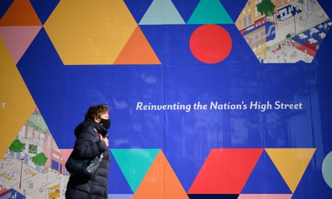 A woman walks past a sign reading ‘reinventing the nation’s high street’ on Oxford Street in London