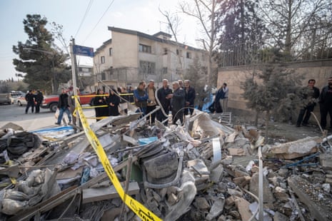 Iranian families gather behind the ruins of a building in Tehran.