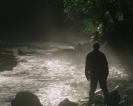 A man looks out over water and rocks