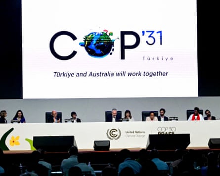 A screen shows the Cop31 logo as delegates in front of it.