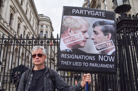 A man in Westminster hold a placard protesting against Partygate