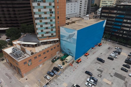 A section of a mural, known as the “Whaling Wall 82,” created by artist Wyland, is visible as part of it on the right side of the building was painted over.