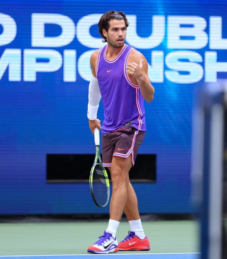 Carlos Alcaraz wearing a Nike vest, untucked, and maroon shorts on court.