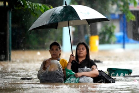 Residents in the Philippines protect their belongings as they negotiate a flooded street caused by heavy rains from Tropical Storm Yagi