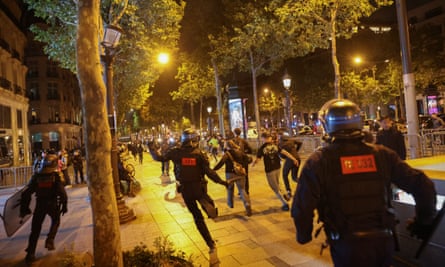 La gente corre seguida por policías en los Campos Elíseos en el centro de París.