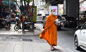 A monk wears a protective face mask along the road side in Bangkok. A monk wears a protective face mask along the road side in Bangkok.