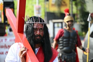 Man in crown of thorns carrying red cross