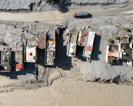 Aerial view of a vehicle driving past houses covered in mud