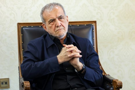 Iranian president Masoud Pezeshkian sat on a chair clasping his hands.