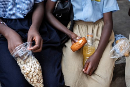 African children seen holding a bag of popcorn, a doughnut and an orange drink