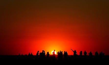 People watch the sunset from a hill in Ealing, west London, on 11 August 2022, after the Met Office issued an amber warning for extreme heat.