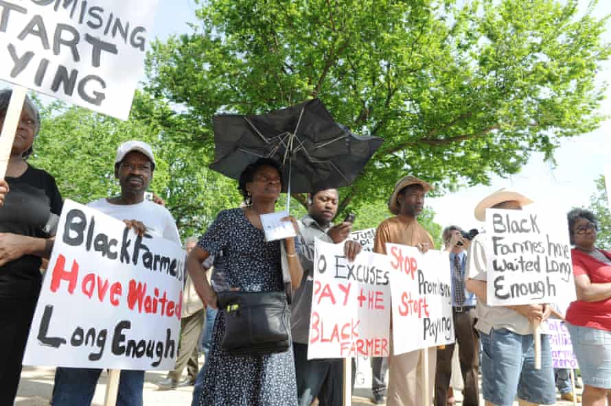 people hold signs saying 'Black farmers have waited long enough' and 'Stop promising, start paying'