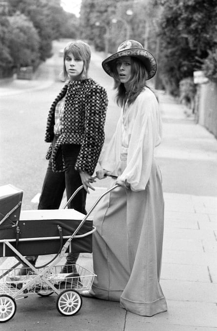 Pop star David Bowie on a street with his wife Angie . He is pushing his three-week-old son in a pram