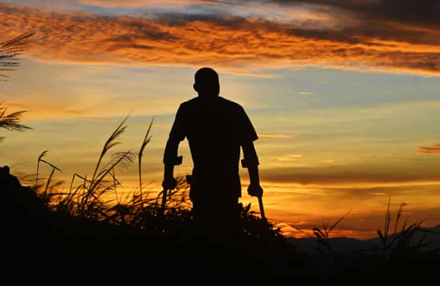A man hiking on crutches at sunrise