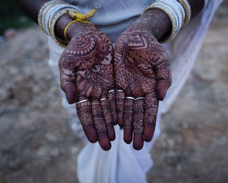 A woman holds out her hands which have patterns drawn in henna all over them