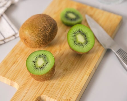 A chopping board with halved and whole kiwi fruit