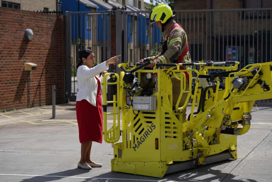 Priti Patel speaking to a firefighter today during a visit to Old Kent Road Fire Station, Southwark, south east London.
