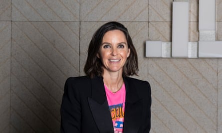 Woman in a black blazer over a pink T-shirt, smiling at the camera