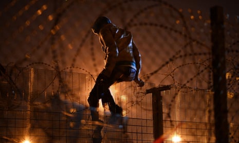 ‘It is an act of welcome’ … a refugee climbs a security fence in Calais, France.