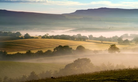 Hills and fields in rolling mists at sunrise.