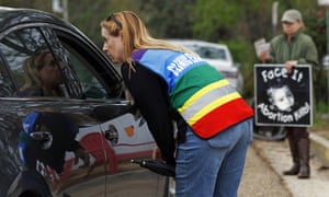 Clinic escort Kim Gibson assists a driver while an abortion opponent protests nearby. The facility is the only one in Mississippi that performs abortions.