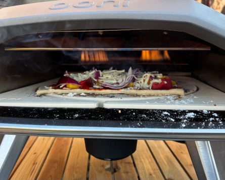 A vegetable pizza with onion, pepper and tomato cooks inside the Ooni Koda 2 pizza oven.