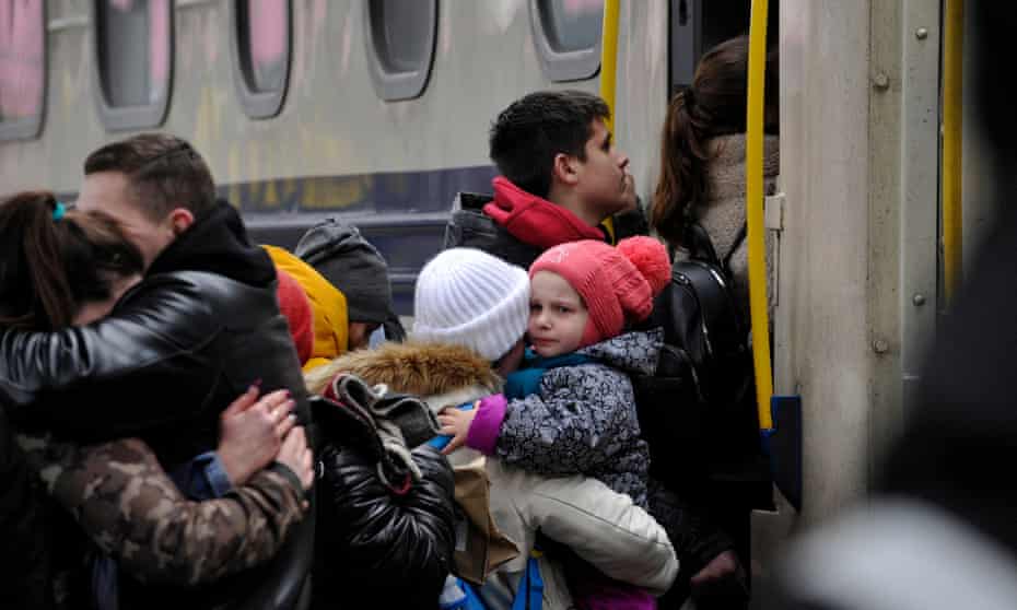 A woman holds a toddler while she waits to board an evacuation train at the central train station in Kyiv