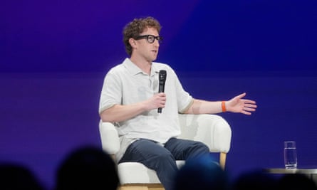 man in white polo, glasses and blue pants sits in chair and speaks into microphone