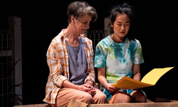 Maude Davey and Susanna Qian sitting next to each other and reading something from K-BOX