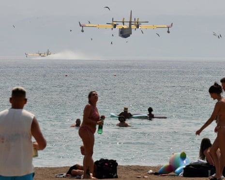 Beachgoers look at the firefighting airplanes scooping water from the Adriatic Sea during a wildfire near Omis, southern Croatia.