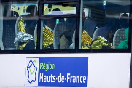 People in a bus wrapped in foil blankets with a sign that reads ‘region Hauts-de-France’