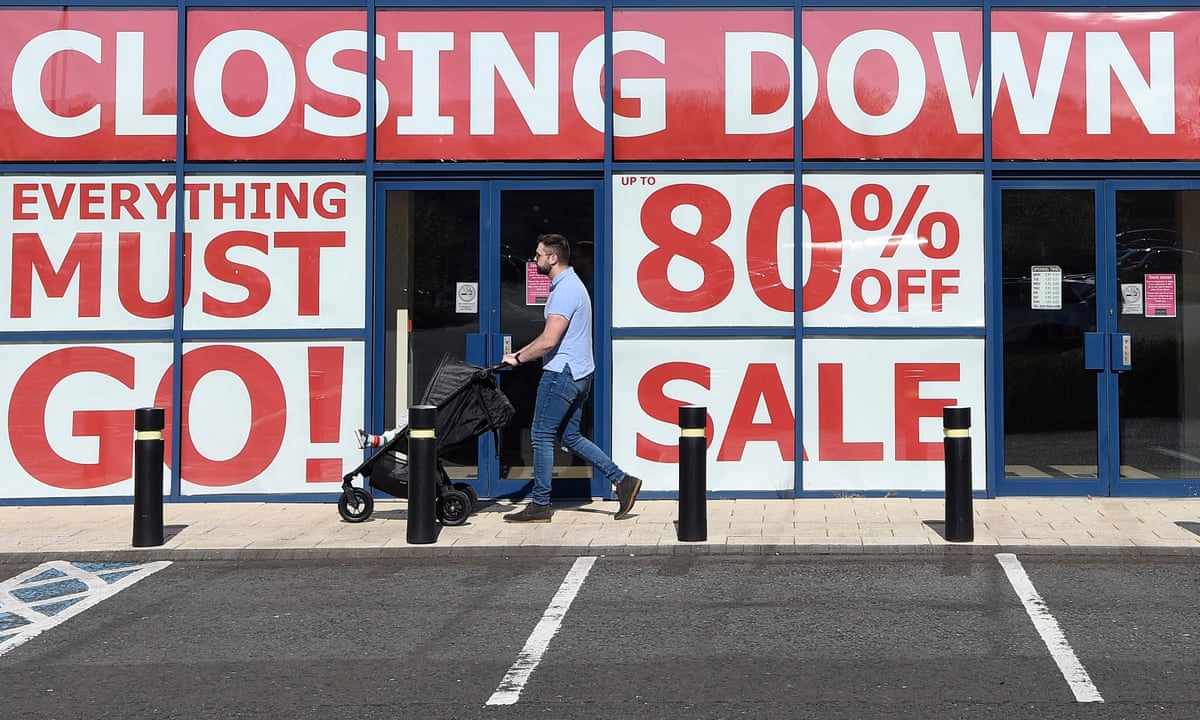 A man walks past a kitchen and furniture store which has an 80% closing down sale on