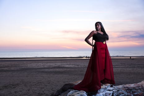 A woman in a flowing red skirt stands at the beach