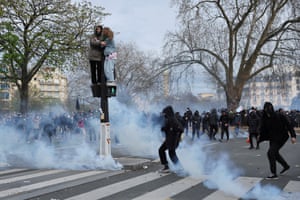 People stand on a pedestrian traffic light during clashes at a demonstration as part of the tenth day of nationwide strikes and protests against the French government’s pension reform in Paris