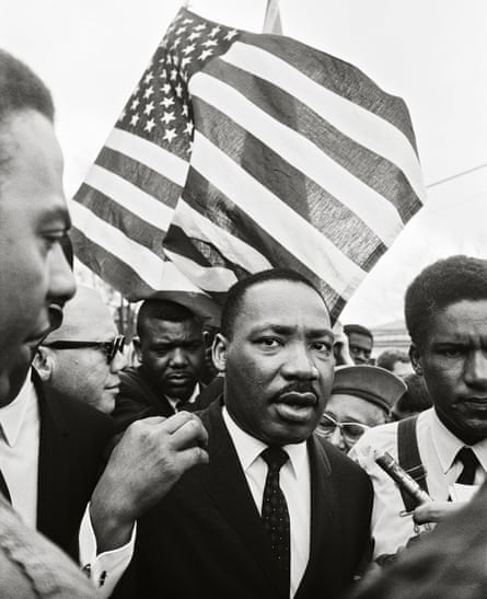 Ralph Abernathy (rear) and Dr. King lead the way on the road to Montgomery. The American flag was a natural symbol for a movement that called on the nation to live up to its principles. 1965 © 2017 Steve Schapiro