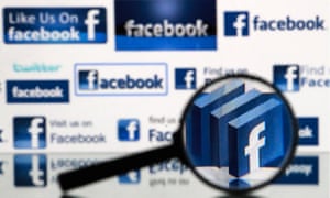 A magnifying glass in front of a computer screen showing Facebook and Twitter logos.