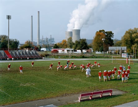 An American football team practising on a field in front of a smoking power plant, West Virginia, 2004