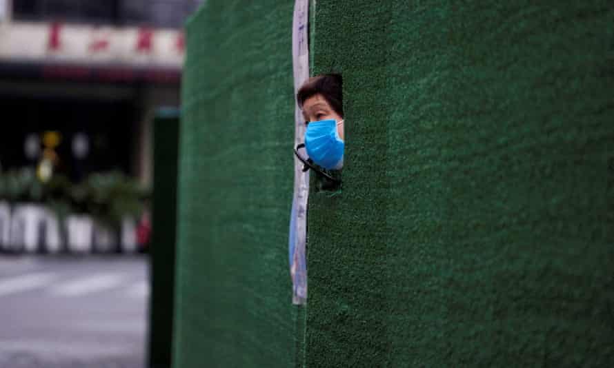 A resident looks out through a gap in the barrier at a residential area during lockdown in Shanghai