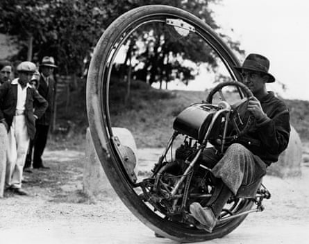 Black and white photograph of Swiss engineer M Gerder at Arles, France on his way to Spain in his Motorwheel, a single-wheeled motorcycle (think a seated lawn mower) that runs on a rail placed within a solid rubber tyre of about 6ft diameter.