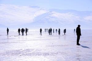 People walk on the frozen surface of Lake Cildir in Kars, Turkey,