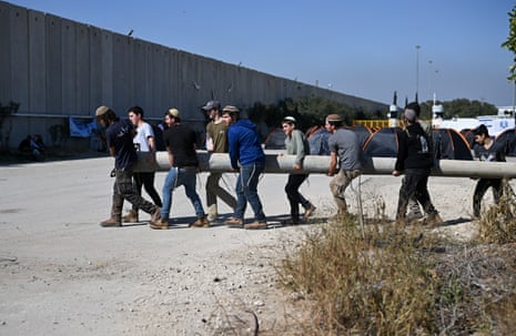 Israeli youth carry a concrete pole, as people protest against the delivery of humanitarian aid to Gaza at the Kerem Shalom crossing, Israel.