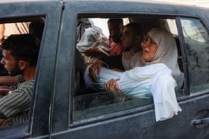 A woman sitting in a car holds the shrouded body of a relative