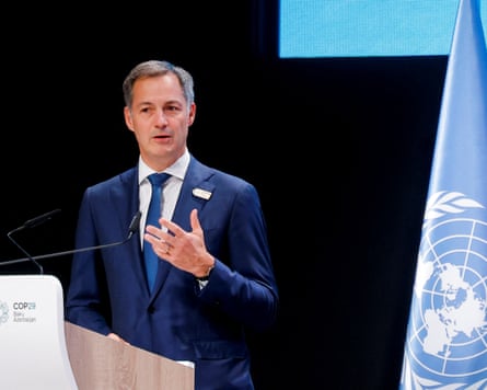 A man in a blue suit and tie speaks at a podium with a United Nations flag in the background