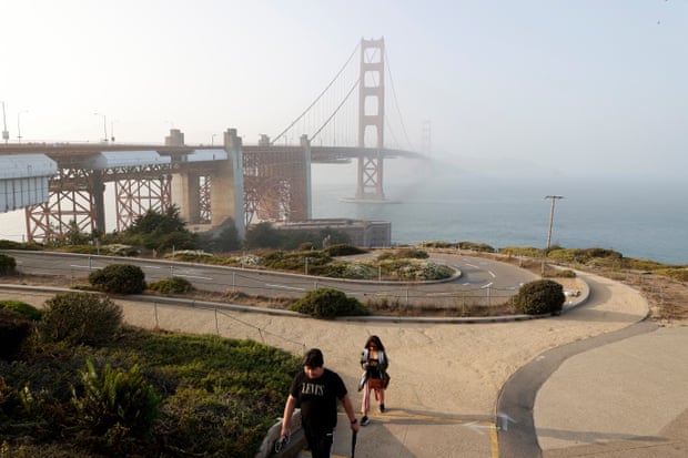 A couple walk up a trail with a hazy view of the Golden Gate Bridge, in San Francisco, California, last week.