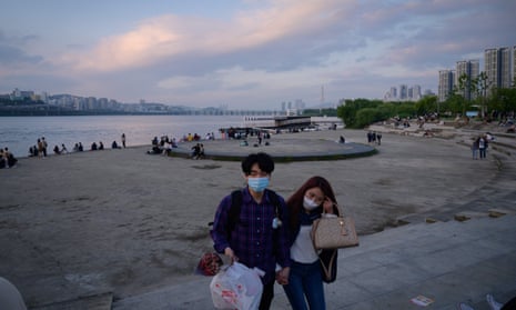 People wearing face masks amid concerns over Covid-19 novel coronavirus walk through a park before the Han river in Seoul