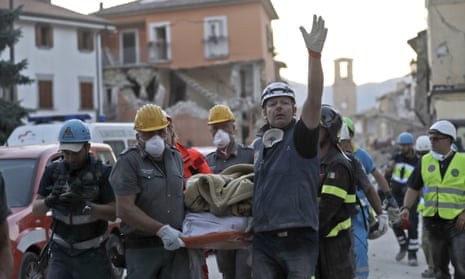 Rescuers carry a body recovered from the rubble in Amatrice.