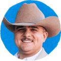 man in cowboy hat and button-down smiling with blue background